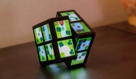 Представлена игровая консоль в виде кубика Рубика с дисплеями на гранях