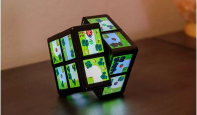 Представлена игровая консоль в виде кубика Рубика с дисплеями на гранях